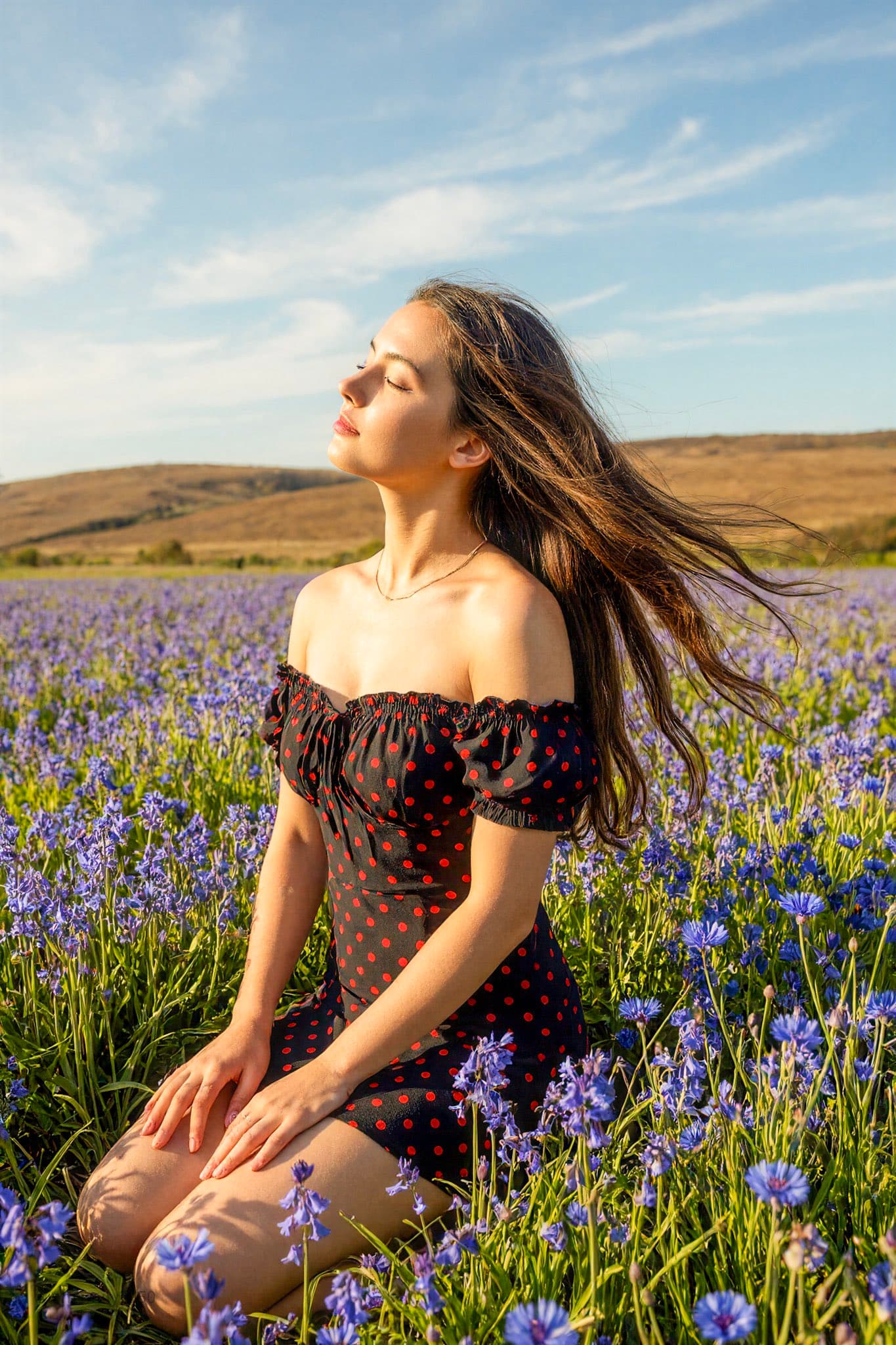 A young woman kneels in the field.